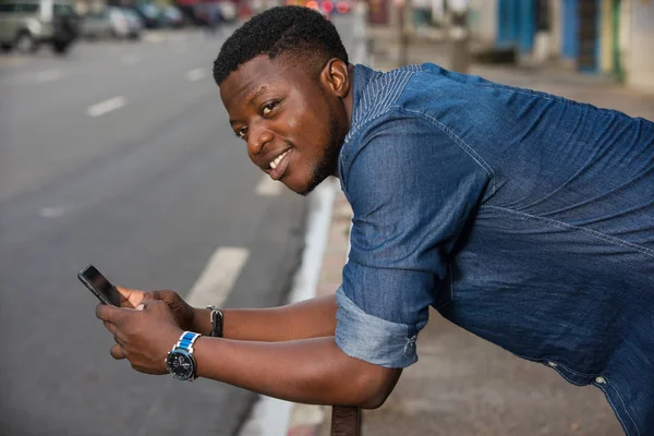 Heureux jeune homme élégant tenant un téléphone mobile à l'extérieur — Photo