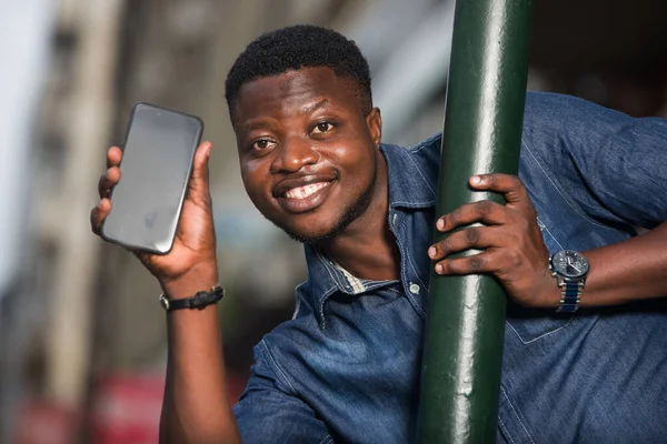 Gros plan d'un jeune Africain avec téléphone portable, souriant . — Photo