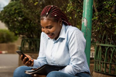 Dışarıda telefonu tutan neşeli genç bir kadın.