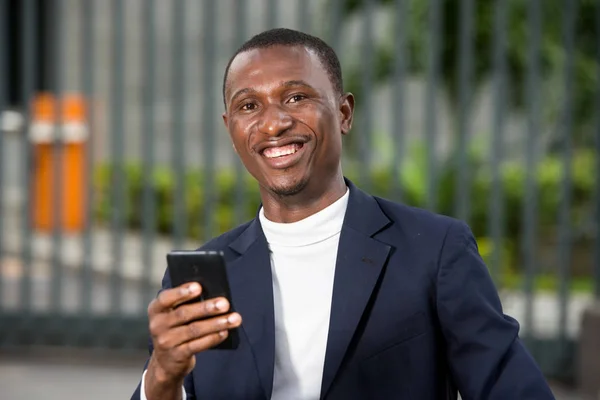 Gros plan de jeune homme africain avec téléphone portable, heureux . — Photo