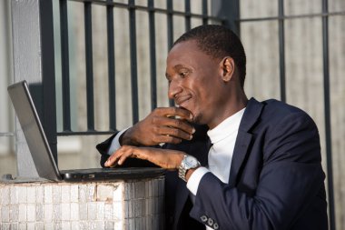 Bir binanın önünde dizüstü bilgisayarla çalışan bir ofis çalışanı resmi