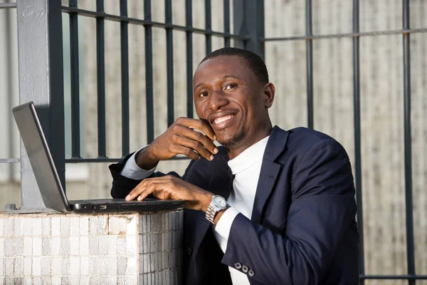 Bir binanın önünde dizüstü bilgisayarla çalışan bir ofis çalışanı resmi