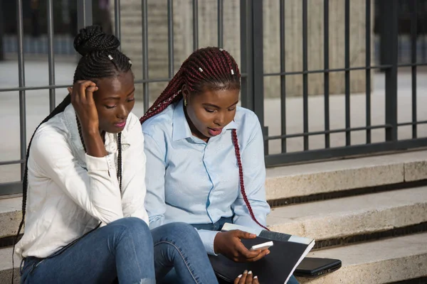 Zwei junge Studentinnen mit Dokumenten sitzen auf einer Treppe im — Stockfoto