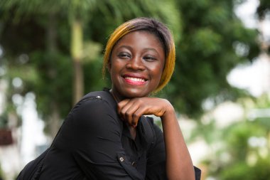 Gülümseyen öğrenci kız dışarıda oturuyor.