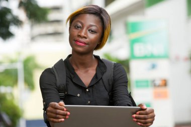 Close-up of young student with laptop, smiling.