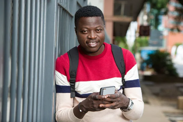 Jeune étudiant avec téléphone portable, souriant . — Photo