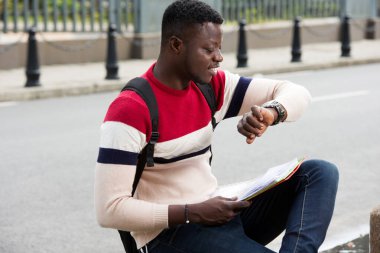Genç öğrenci saatine bakıyor.