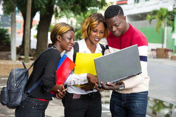 Öğrenciler dersten sonra dizüstü bilgisayara bakıp gülümsüyor..