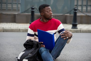 Kampustaki notları okuyan yakışıklı bir üniversiteli. Dışarıda oturan mutlu bir öğrenci. Eğitim