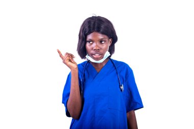 Mavi üniformalı güzel bir bayan doktor parmağıyla kameraya gülümsüyor..