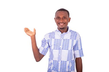 Beyaz arka planda duran gömlekli genç bir adam avuç içini gösteriyor ve gülümseyen kameraya bakıyor..