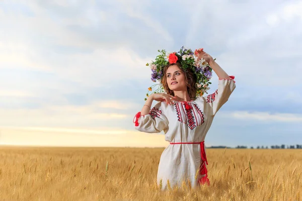 Красива дівчина одягнена в національний одяг і вінок у полі — стокове фото