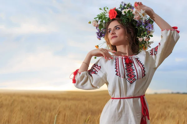 Menina bonita vestida com roupas nacionais e grinalda no campo — Fotografia de Stock