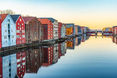 Nidelva Nehri 'ni çevreleyen renkli kereste evlerinin günbatımı manzarası 