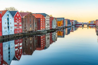 Nidelva Nehri 'ni çevreleyen renkli kereste evlerinin günbatımı manzarası 