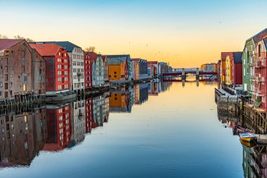 Nidelva Nehri 'ni çevreleyen renkli kereste evlerinin günbatımı manzarası 