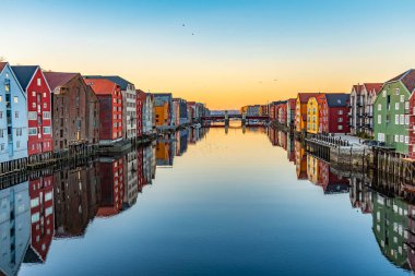 Sunset view of colorful timber houses surrounding river Nidelva  clipart
