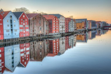 Nidelva Nehri 'ni çevreleyen renkli kereste evlerinin günbatımı manzarası 