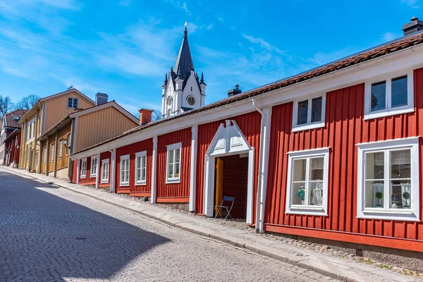 Vit kyrka i Nora sedd bakom timmerhus, Sverige — Stockfoto