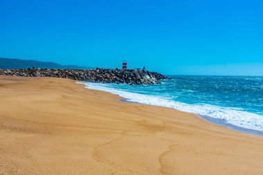 İnsanlar Portekiz 'de Nazare sahilinde güneşli bir günün tadını çıkarıyorlar.