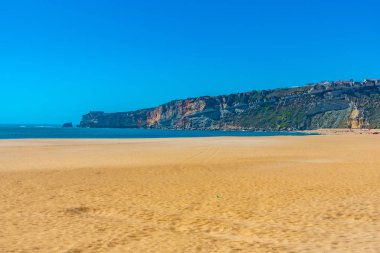 İnsanlar Portekiz 'de Nazare sahilinde güneşli bir günün tadını çıkarıyorlar.