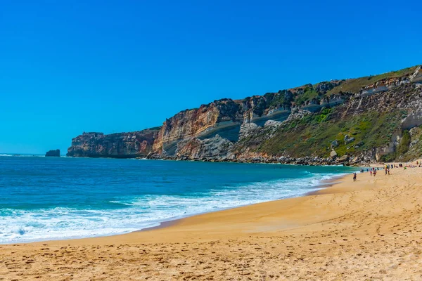 Folk njuter av en solig dag på en strand i Nazare i Portugal — Stockfoto