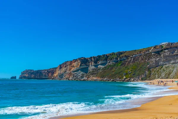 Folk njuter av en solig dag på en strand i Nazare i Portugal — Stockfoto