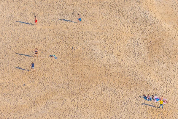 Вид с воздуха на людей, наслаждающихся солнечным днем на пляже в Назаре — стоковое фото