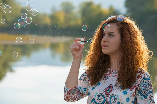 Beautiful girl makes bubbles of soap — Stock Photo, Image
