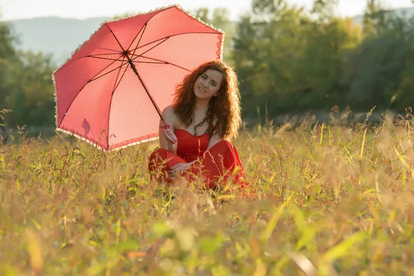 Red - haired meisje in een rode jurk — Stockfoto