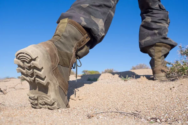 Pieds humains en bottes rugueuses de randonnée marchant sur le sable dans un désert, gros plan, grand angle, mise au point sélectionnée — Photo