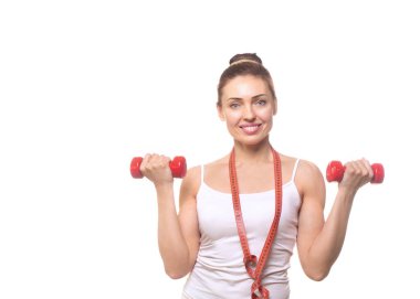 Güzel gülümseyen kadın koç elinde kırmızı bir dambıl tutuyor ve beyaz tenli kaslı kollar gösteriyor. Aktif yaşam tarzı reklamı yapan beyaz kadın..