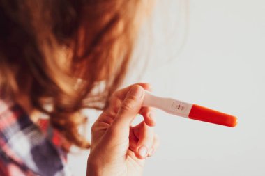 Genç bir kadın hamilelik testi yapıyor ve sonuç pozitif.