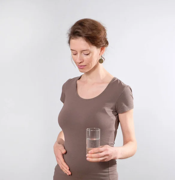 Junge Schwangere hält ein Glas Wasser in der Hand — Stockfoto