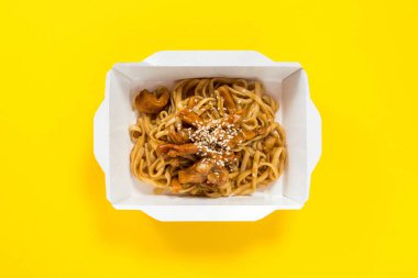 Paket yemek: dilimlenmiş domuz ve susam tohumlu şehriye; sarı arka plan