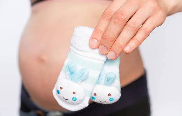 Schwangere Hält Kleine Socken Auf Dem Hintergrund Des Bauches Nahaufnahme — Stockfoto