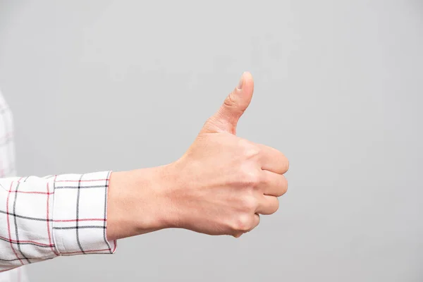 Female hand showing a thumb up sign on a neutral background