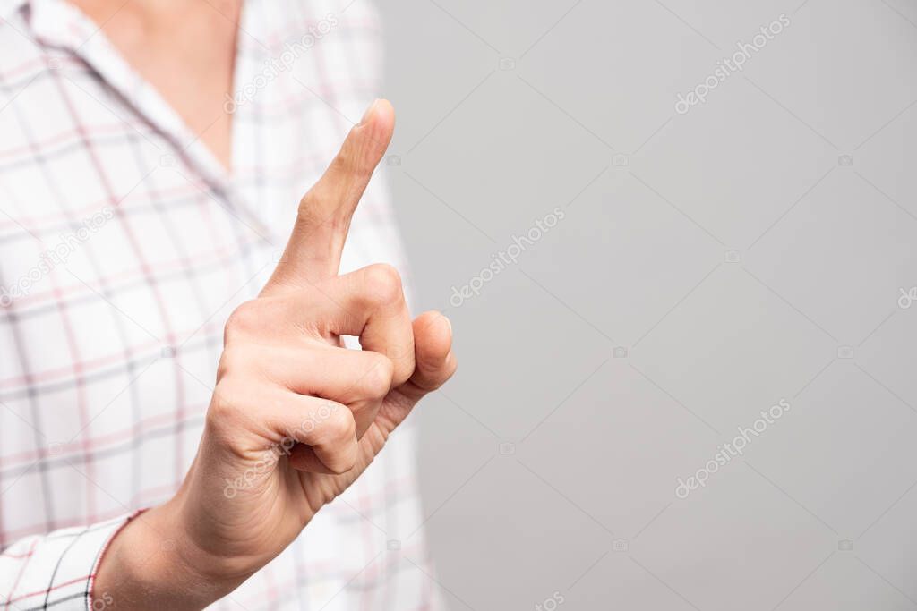 Female hand shows an index finger up on a neutral background