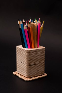 Siyah arkaplanda kalem kutusundaki renkli kalemler.