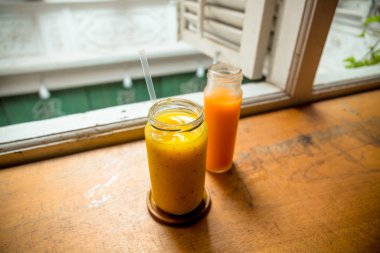 İki farklı içecek çeşidine yakın çekim, soğuk basılmış havuç suyu ve mango suyu..