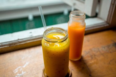 İki farklı içecek çeşidine yakın çekim, soğuk basılmış havuç suyu ve mango suyu..