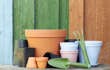 Terracotta kil saksıları ile siyah plastik kaplar ve bahçe aletleri ahşap masa üzerinde renkli parlak rustik arka plan, çocuk odası ve bahçe konsepti, yakın plan, kopyalama alanı