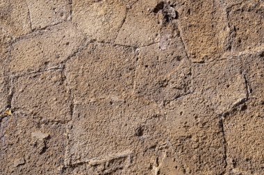 İşlenmiş kumtaşından yapılmış eski bir Roma tapınağının eski bir taş duvarının parçası. Geçmişi. Ocher 'in rengi.