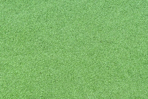 A fragment of artificial carpet with imitation of bright green grass lawn. Background. Pattern.