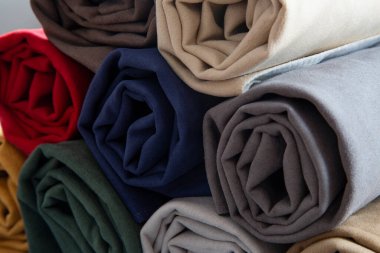 Sade bir arkaplanda birçok renkli kumaş ruloları