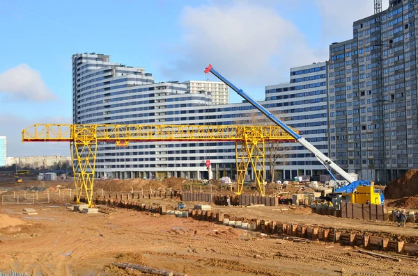 Gantry crane and auto crane working at construction site. Digging a pit for the building of an underground tunnel of the metro line. Subway construction project, Minsk, Belarus, Aerodromnaya street