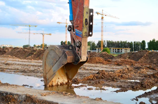 Excavator bucket on the construction site at sunset background and of the blue sky. Land Clearing, grading, pool excavation, utility trenching, utility trenching and foundation digging during