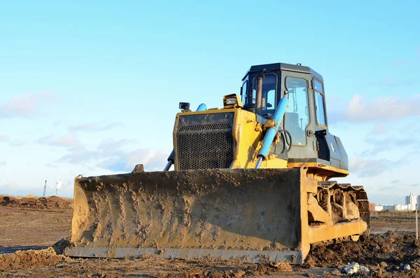 Bulldozer during of large construction jobs at building site. Land clearing, grading, pool excavation, utility trenching and foundation digging. Crawler tractor,  dozer, earth-moving equipment.