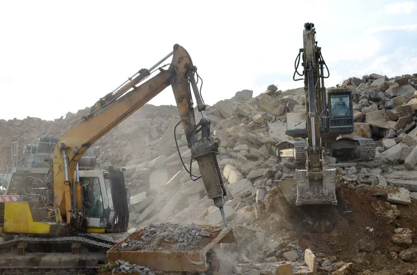 Salvaging and recycling building and construction materials. Excavator with hydraulic hammer work at landfill with concrete demolition waste. Reuse concrete for new construction