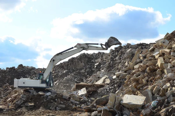 Salvaging and recycling building and construction materials. Industrial waste treatment plant. Excavator work at landfill with concrete demolition waste. Re-use concrete for new construction